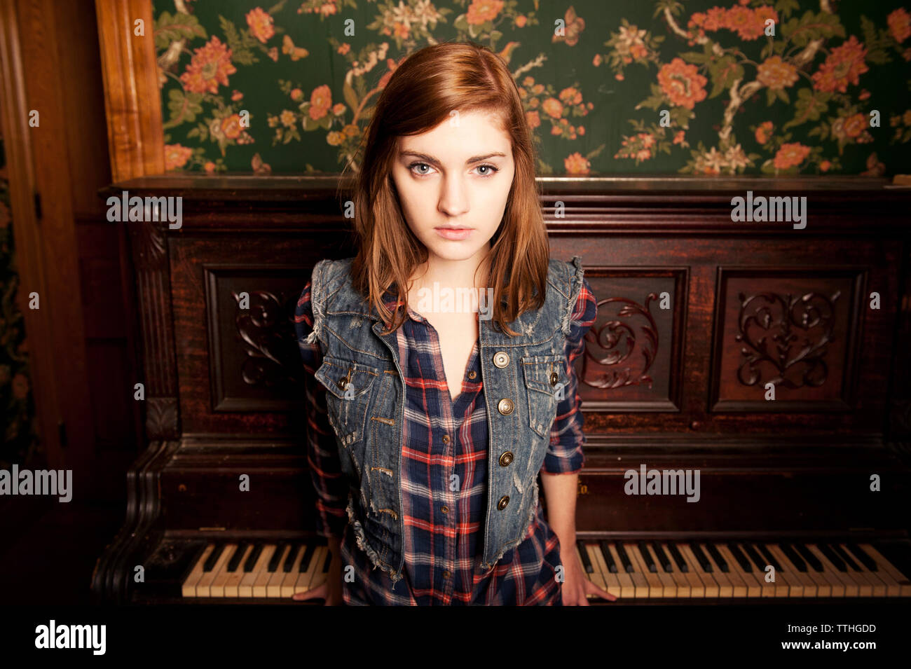 Ritratto di giovane donna in piedi contro il piano a casa Foto Stock