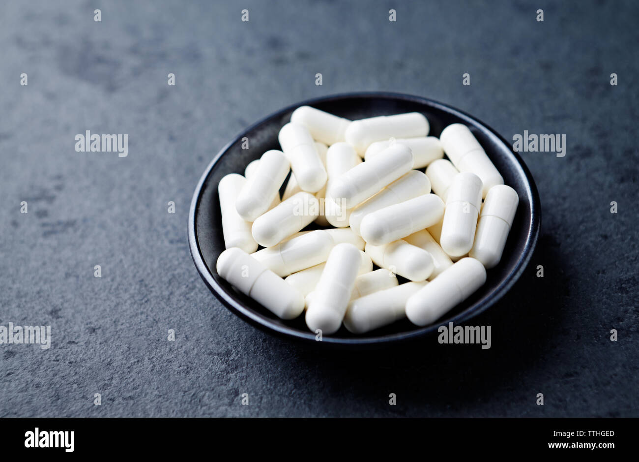 Arginina alfa-chetoglutarato (AAKG) capsule. Bodybuilding integratori alimentari in pietra scura sullo sfondo. Close up. Copia dello spazio. Foto Stock