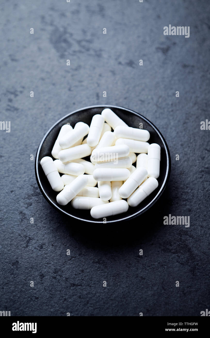 Arginina alfa-chetoglutarato (AAKG) capsule. Bodybuilding integratori alimentari in pietra scura sullo sfondo. Close up. Copia dello spazio. Foto Stock