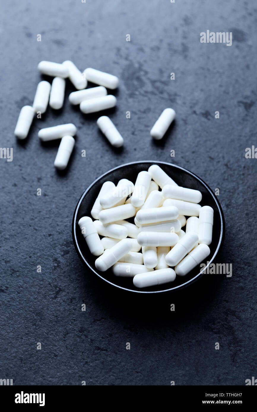 Arginina alfa-chetoglutarato (AAKG) capsule. Bodybuilding integratori alimentari in pietra scura sullo sfondo. Close up. Copia dello spazio. Foto Stock