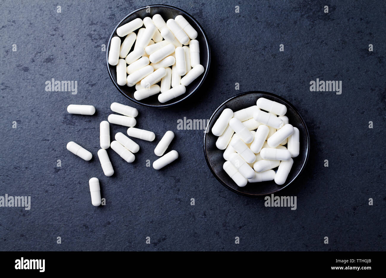 Arginina alfa-chetoglutarato (AAKG) e creatina capsule. Bodybuilding integratori alimentari in pietra scura sullo sfondo. Vista dall'alto. Copia dello spazio. Foto Stock