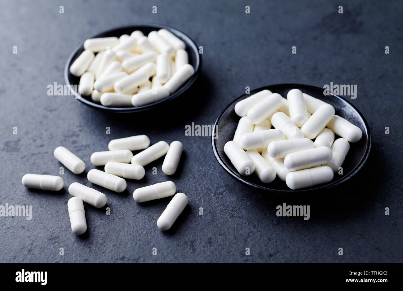 Arginina alfa-chetoglutarato (AAKG) e creatina capsule. Bodybuilding integratori alimentari in pietra scura sullo sfondo. Copia dello spazio. Foto Stock