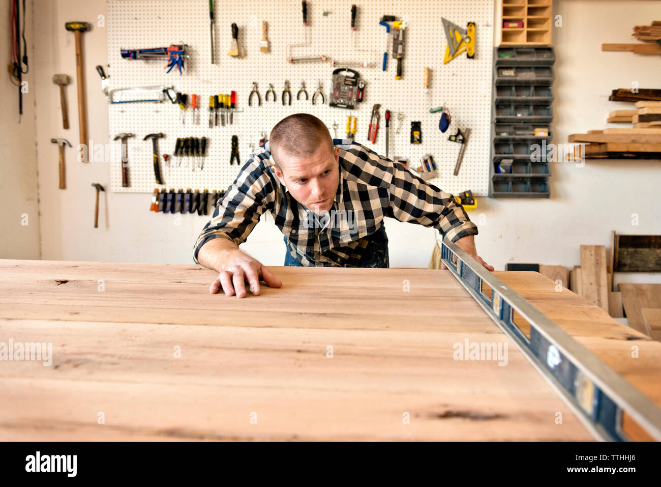 Carpenter controllando il legno con attrezzature di officina Foto Stock