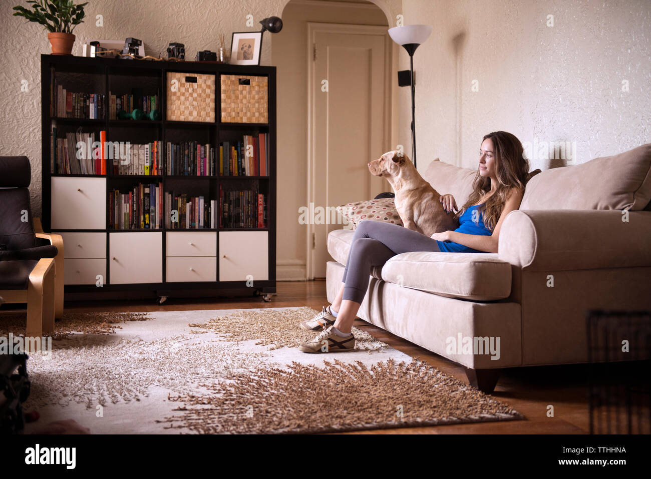 Donna seduta con il cane sul divano di casa Foto Stock
