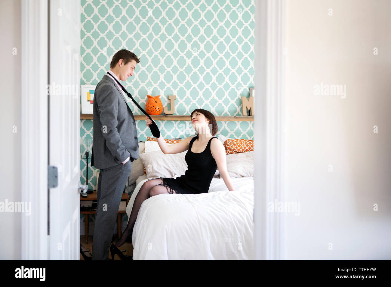 Donna appassionata di tiro dell'uomo cravatta in camera da letto a casa Foto Stock