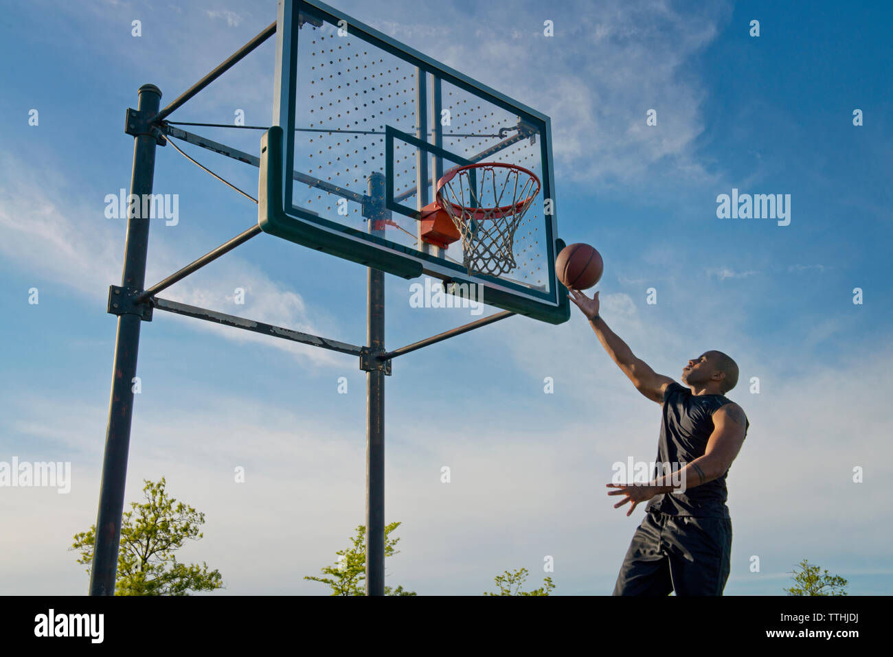 Basso angolo di vista sportivo dunking palla in hoop --contro sky Foto Stock