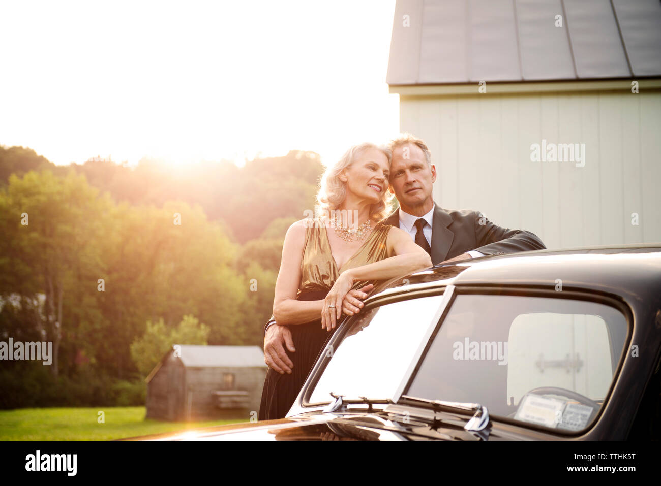 Romantico coppia senior in piedi dall'auto d'epoca durante la giornata di sole Foto Stock