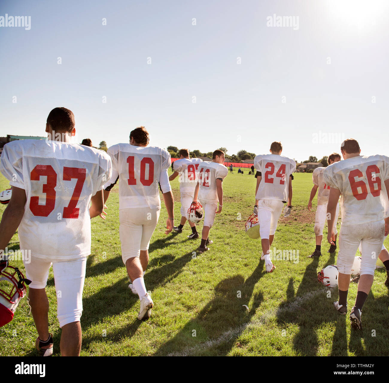 Vista posteriore del football americano giocatori camminando sul campo contro il cielo chiaro Foto Stock