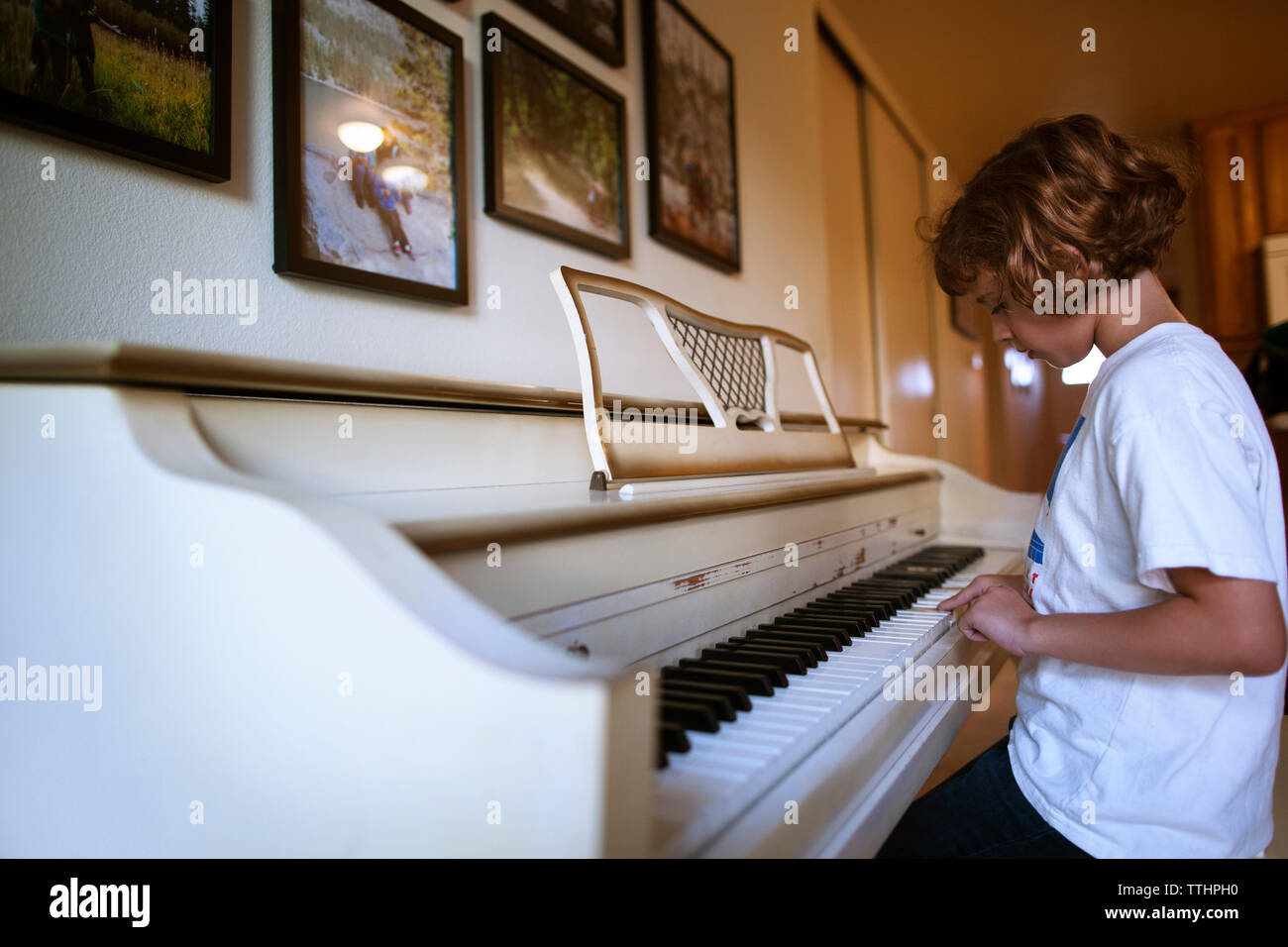 Vista laterale di una ragazza suonare il pianoforte a casa Foto Stock