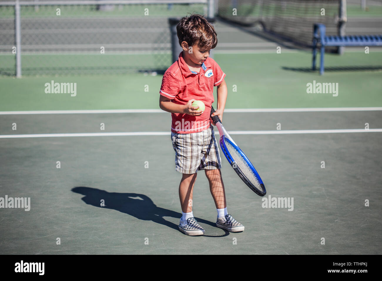 Ragazzo holding racchetta da tennis e la sfera mentre permanente sulla corte Foto Stock