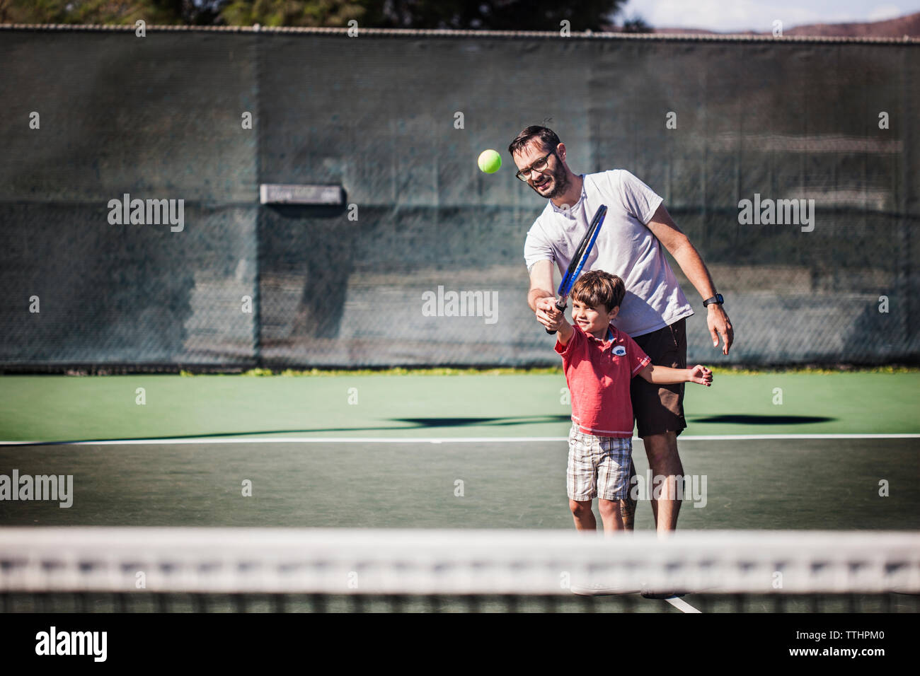 Padre e figlio giocando a tennis su corte Foto Stock