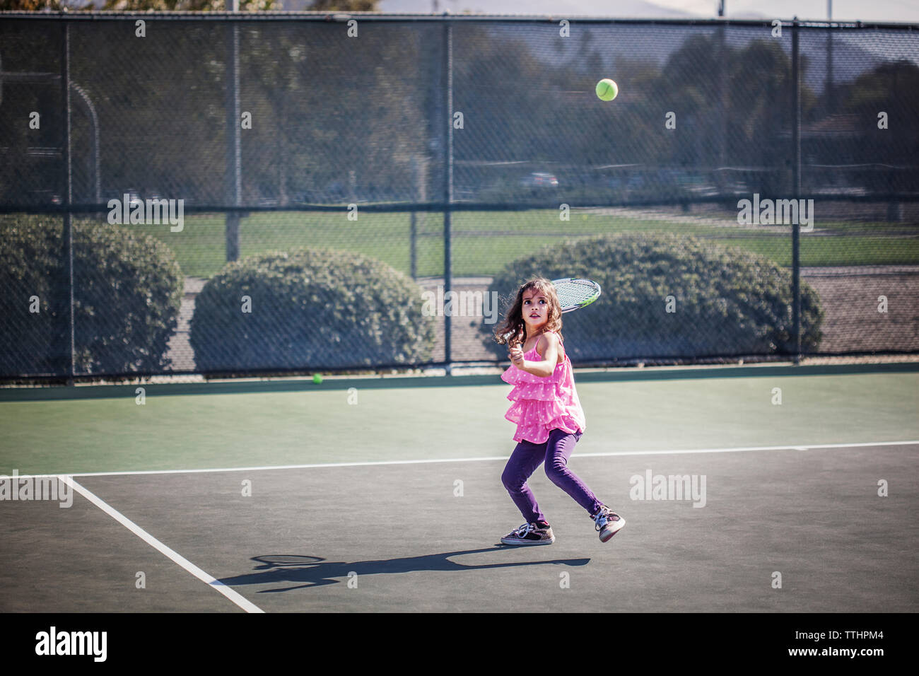 Ragazza cercando mentre gioco a tennis su corte Foto Stock