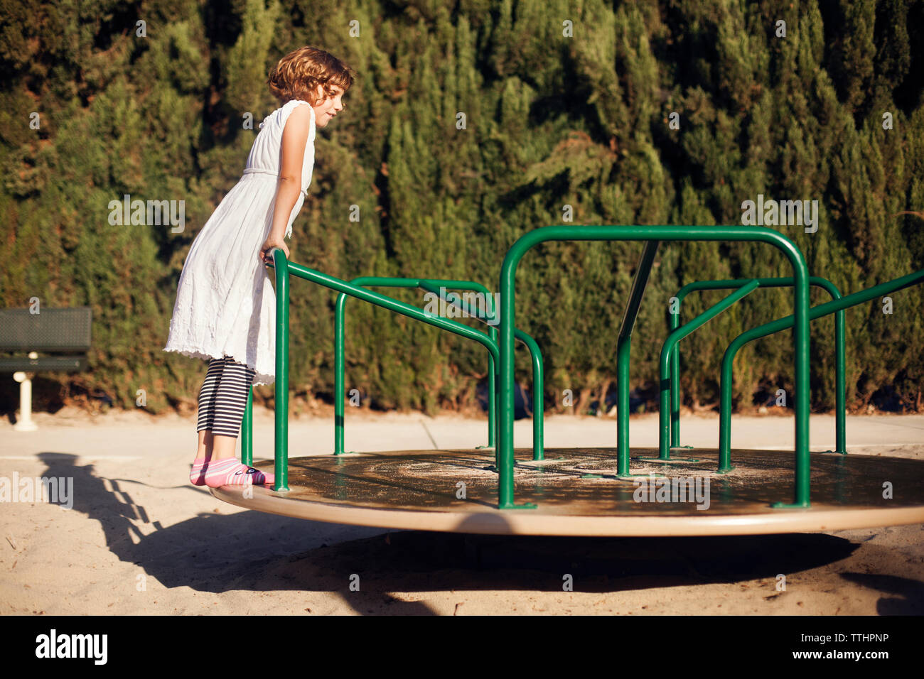 Ragazza in piedi su merry-go-round a park Foto Stock