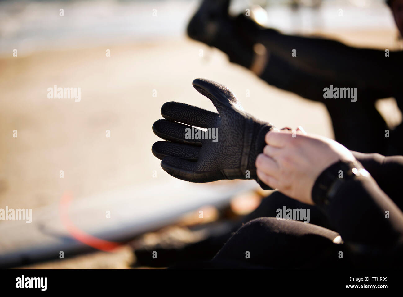 Immagine ritagliata di mano indossando guanti di sport in spiaggia Foto Stock