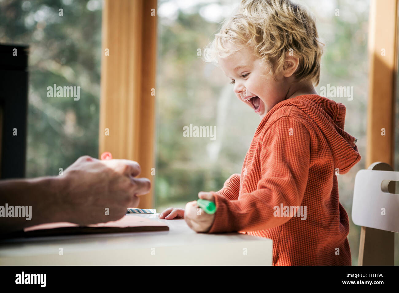 Allegro ragazzo di imparare a scrivere mentre è seduto da padre a casa Foto Stock