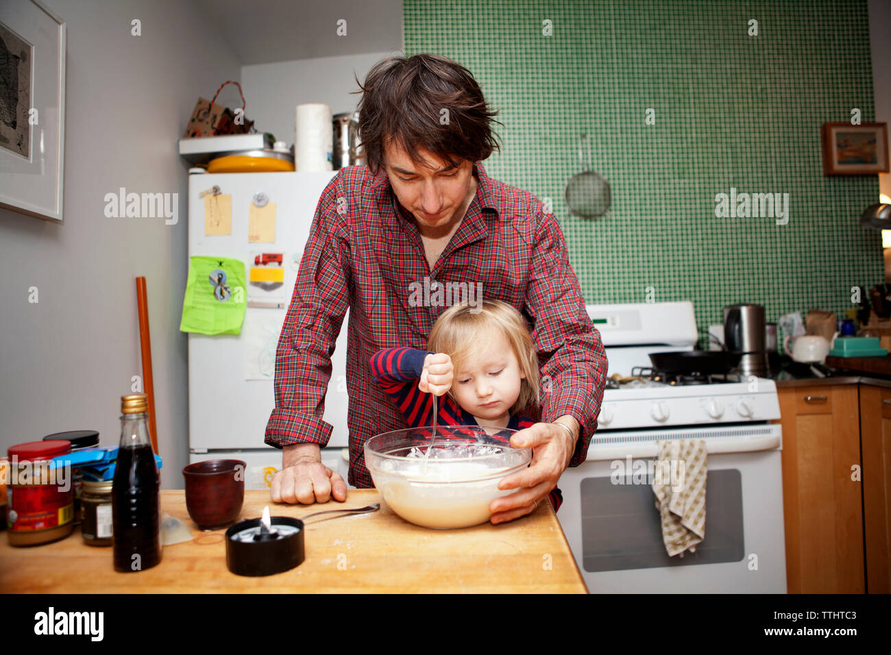 Padre che assiste il figlio in cottura a casa Foto Stock