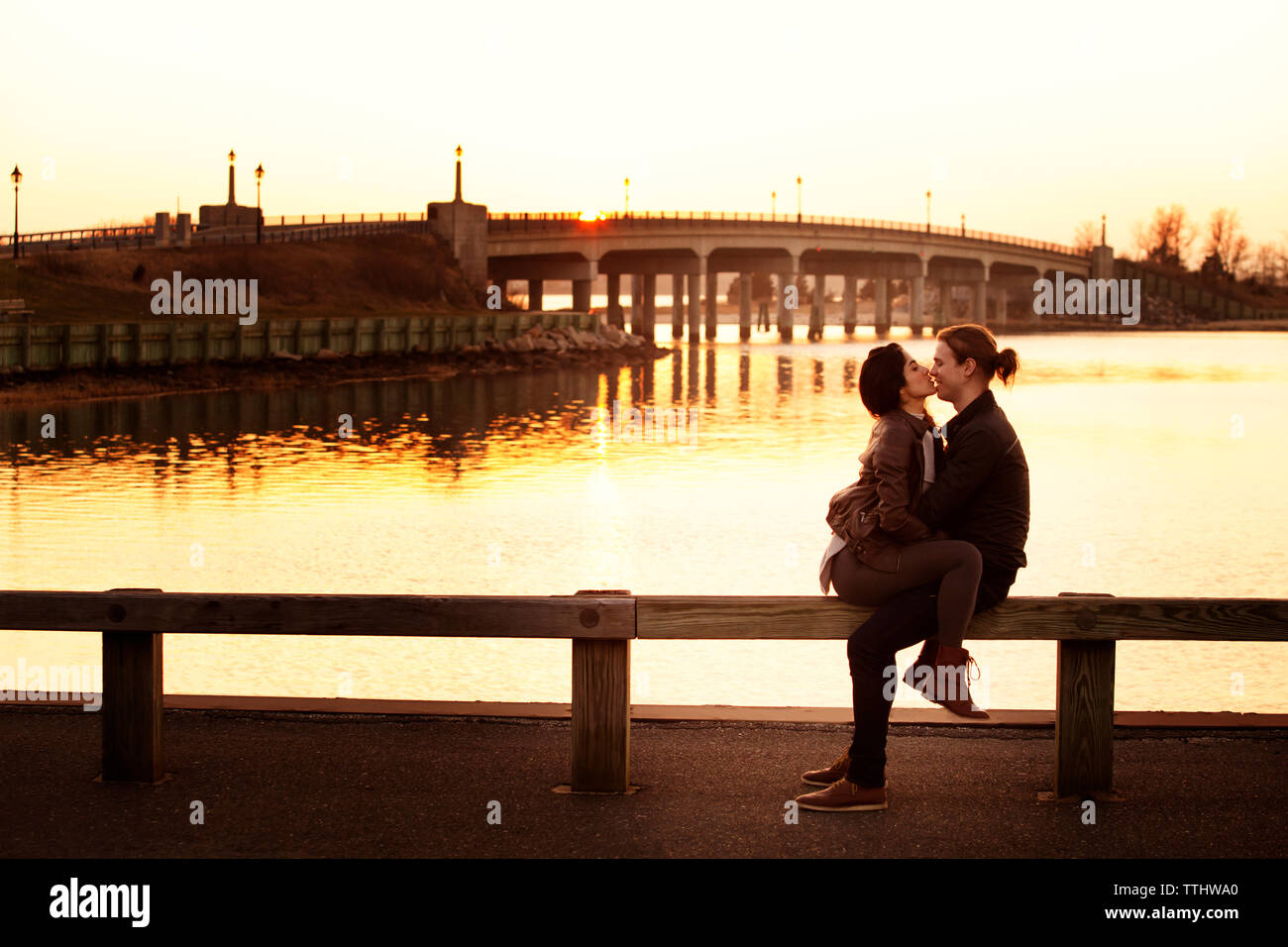 Coppia romantica seduto sulla ringhiera contro sky durante il tramonto Foto Stock