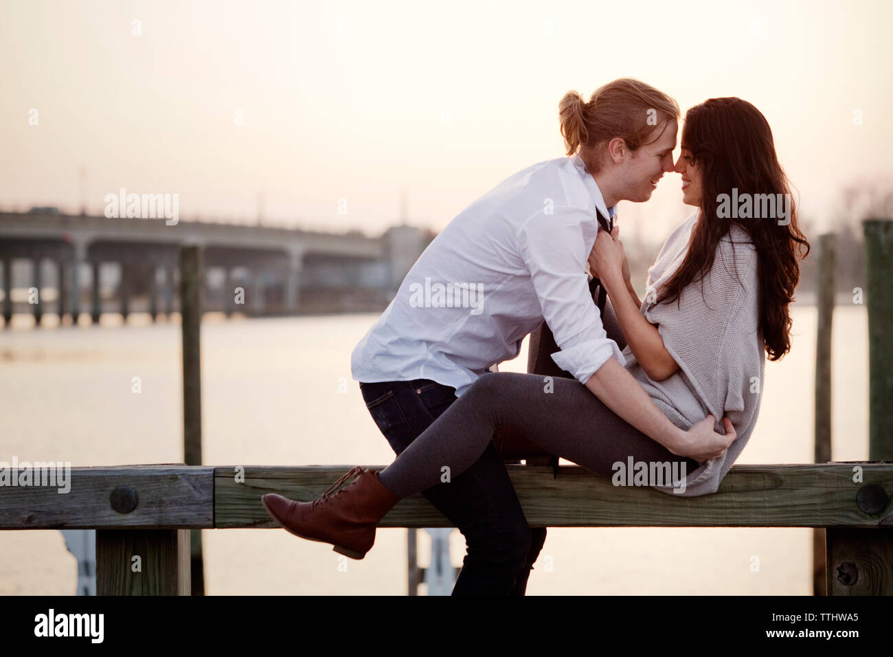 Felice coppia romantica seduto sulla ringhiera contro sky Foto Stock