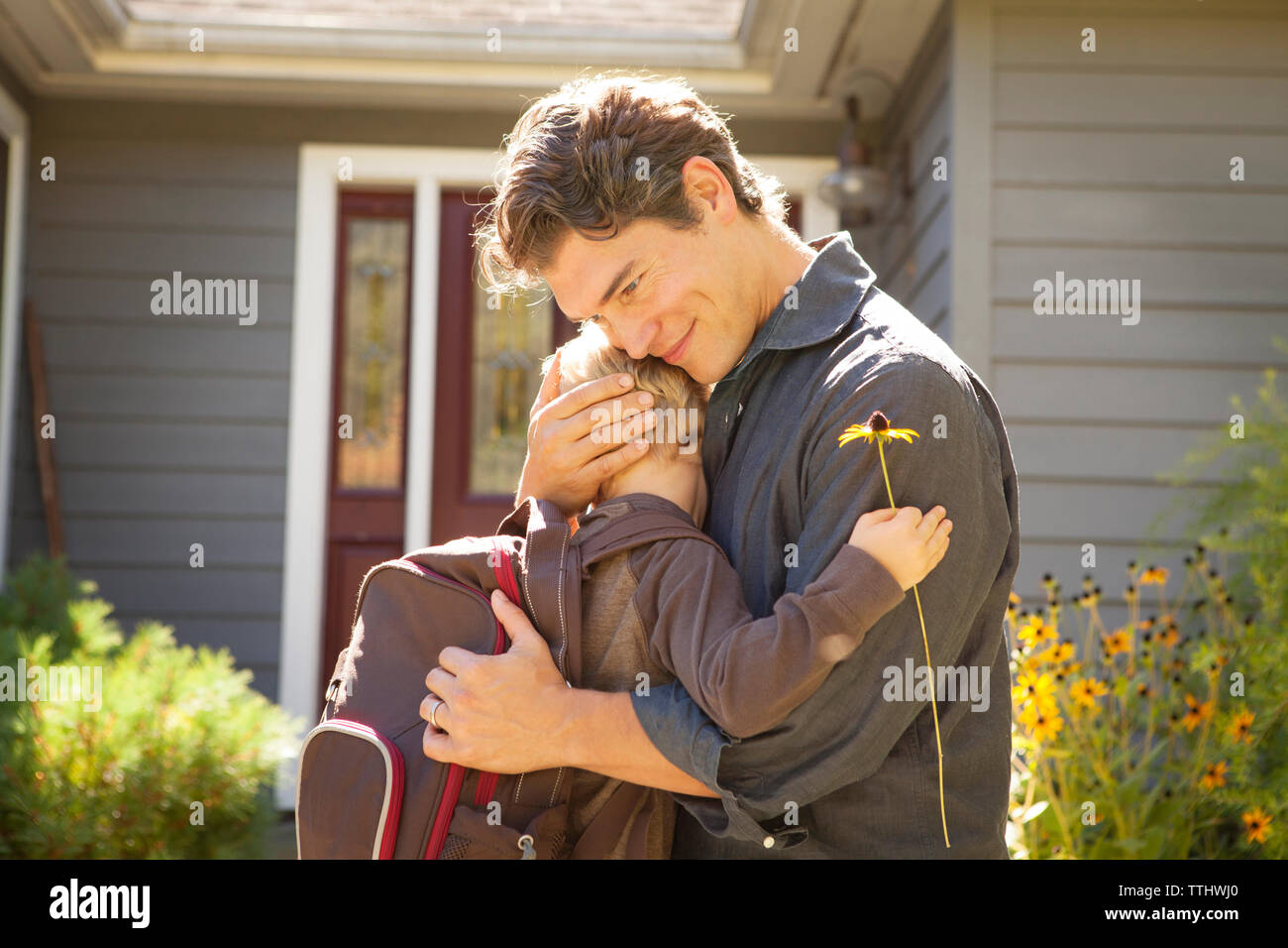 Padre abbracciando il figlio fuori casa Foto Stock