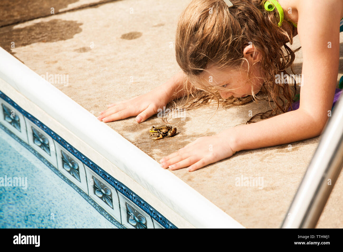 Ragazza che gioca con la rana a bordo piscina Foto Stock