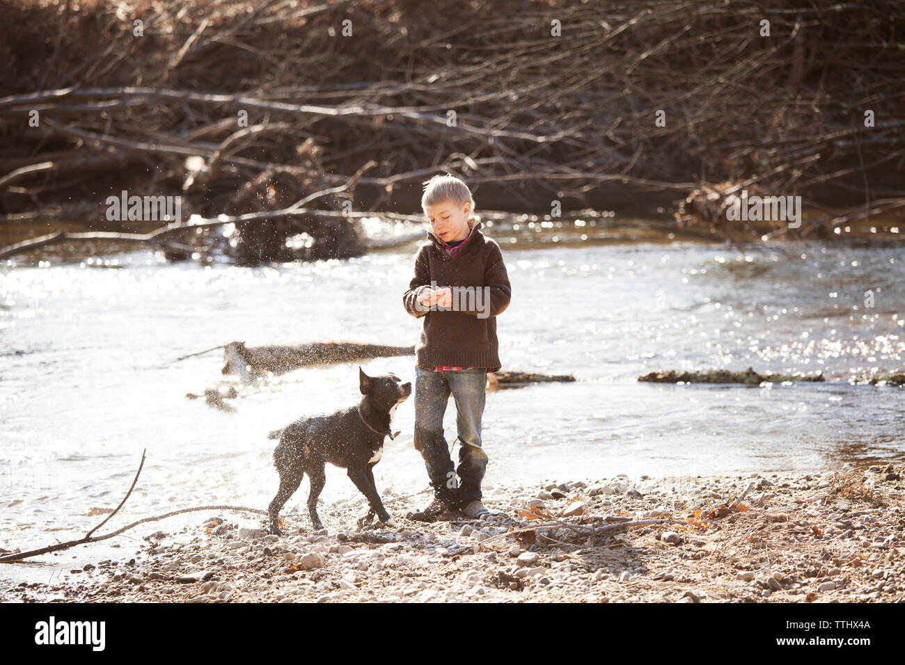 Ragazzo che sta con il cane dal fiume Foto Stock