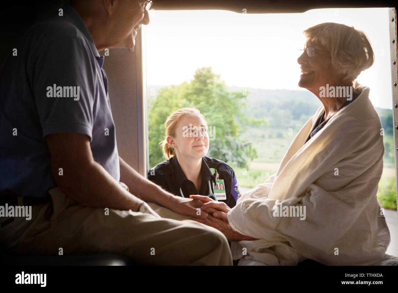 Paramedic guardando il paziente seduto con il marito in ambulanza Foto Stock