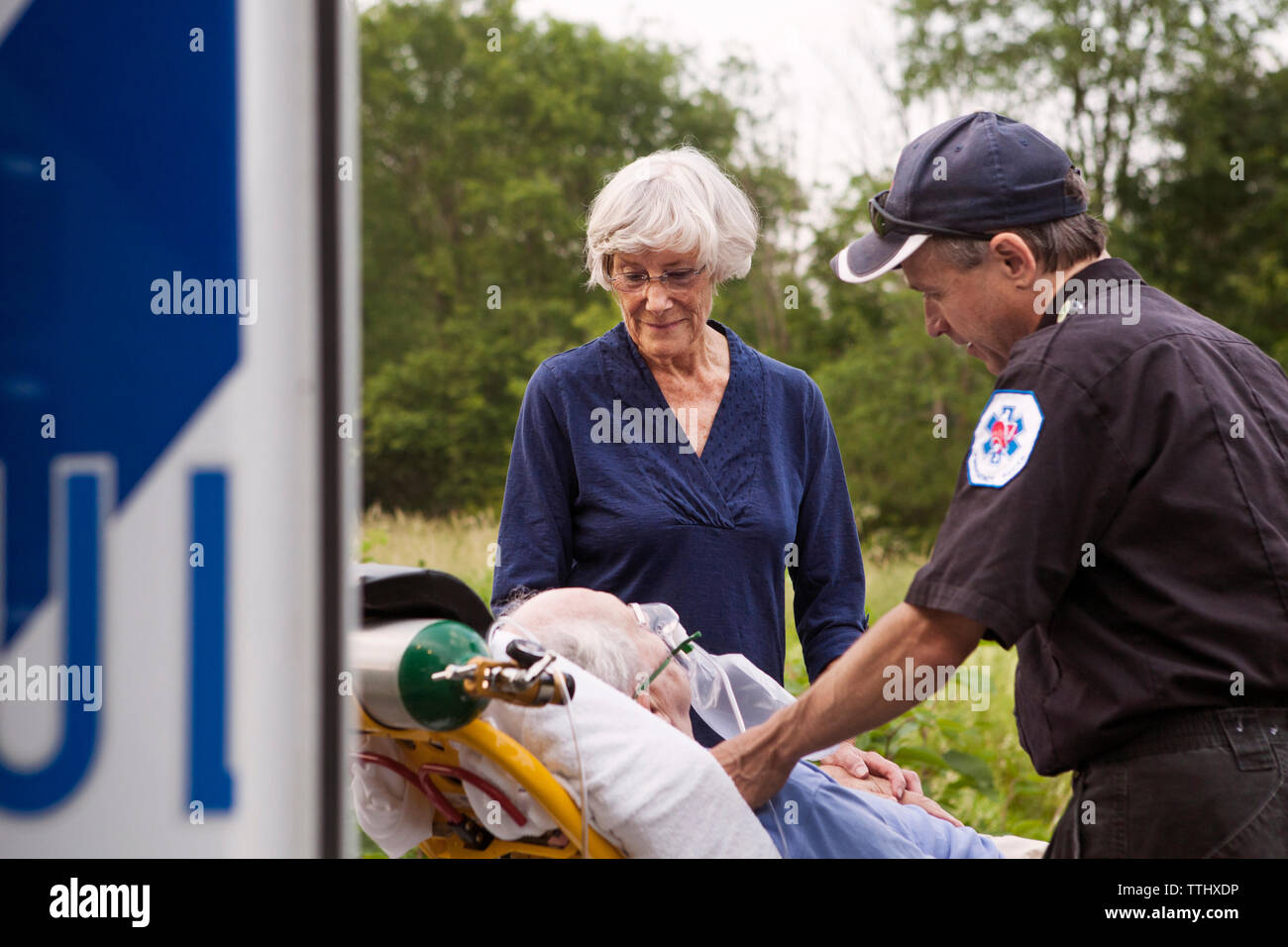 Paramedico e donna guardando il paziente sdraiato sulla barella in ospedale Foto Stock