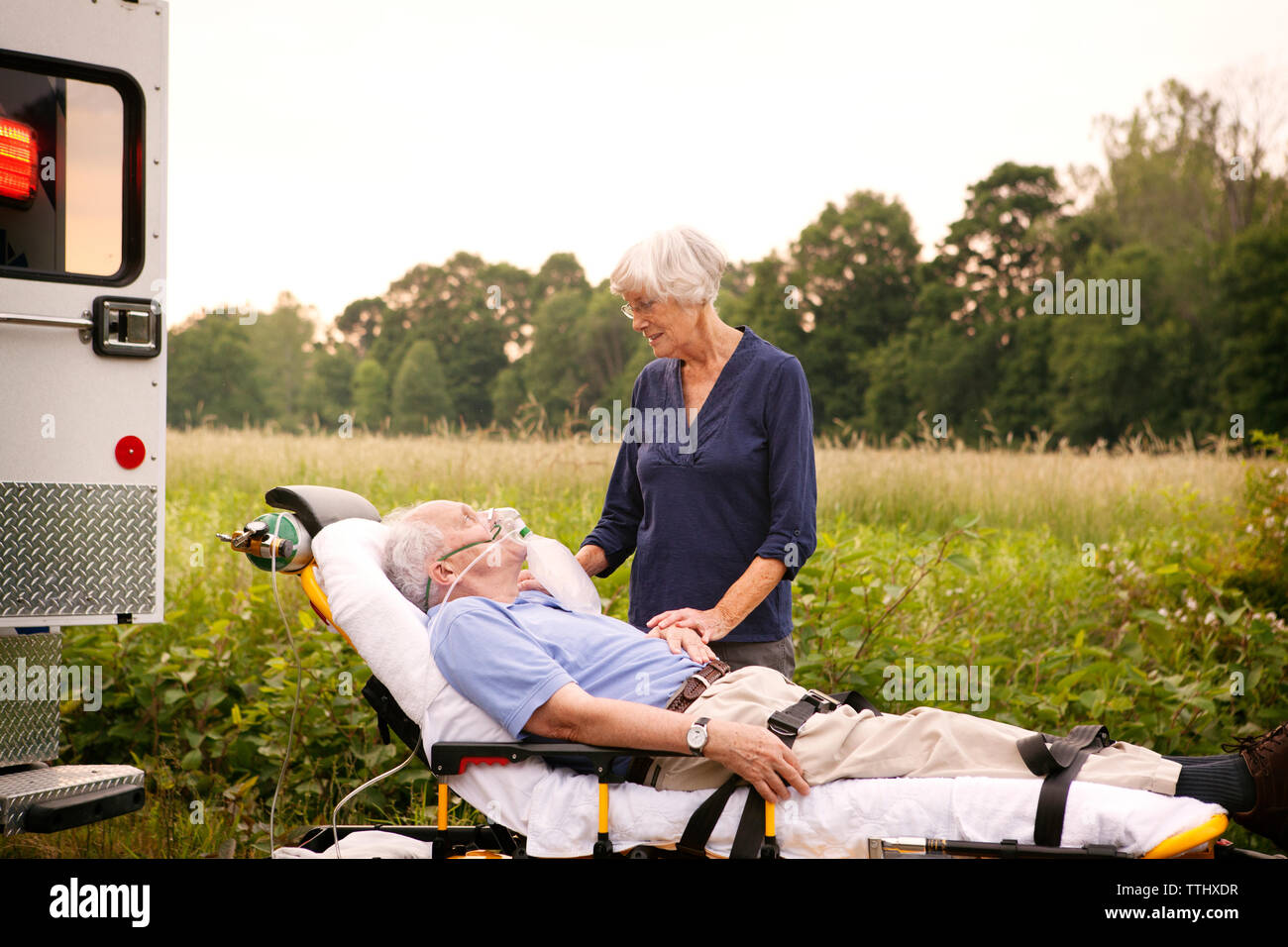 Donna in piedi dal paziente sdraiato sulla barella in ospedale Foto Stock