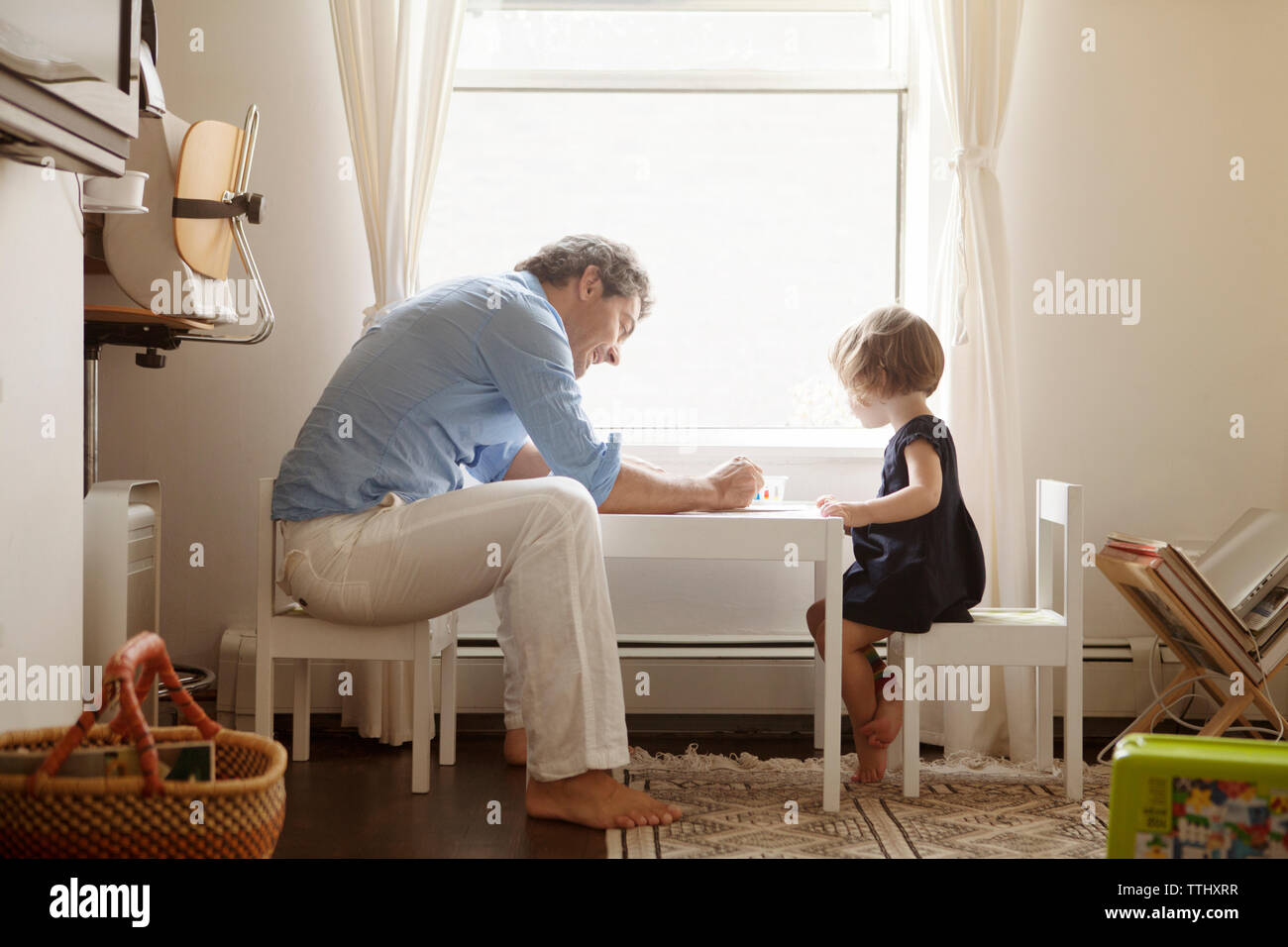 Vista laterale del padre figlia di insegnamento colorazione a tavola in casa Foto Stock