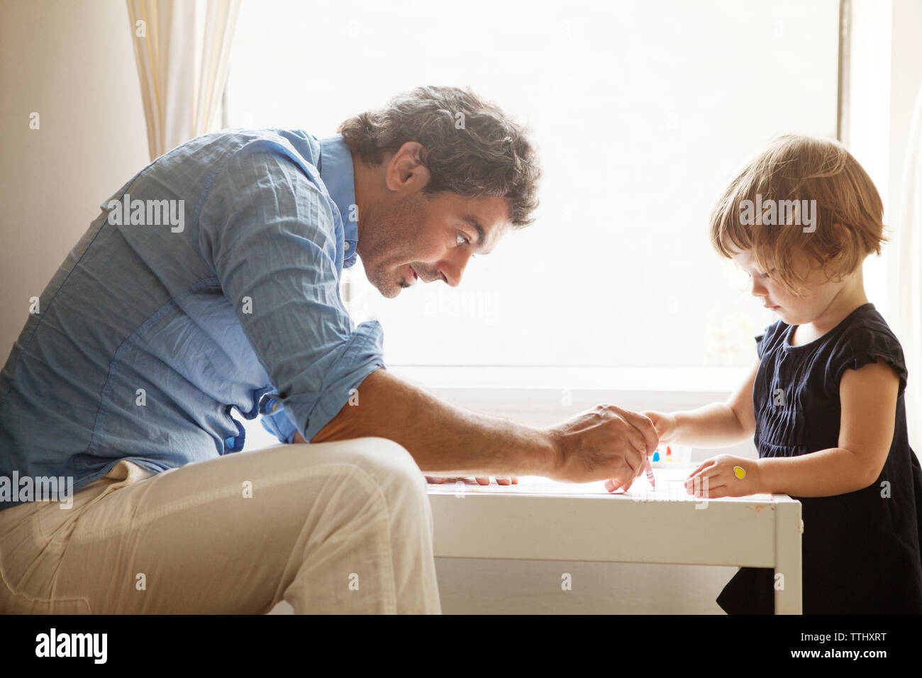 Padre figlia di insegnamento colorazione a tavola in casa Foto Stock