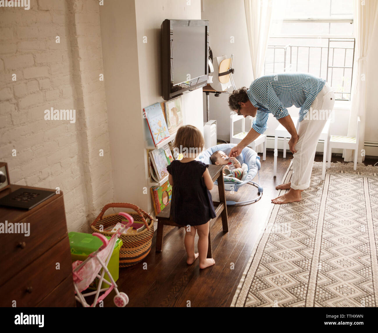 Padre alimentazione ghiaccioli per bambina dalla figlia in piedi a casa Foto Stock