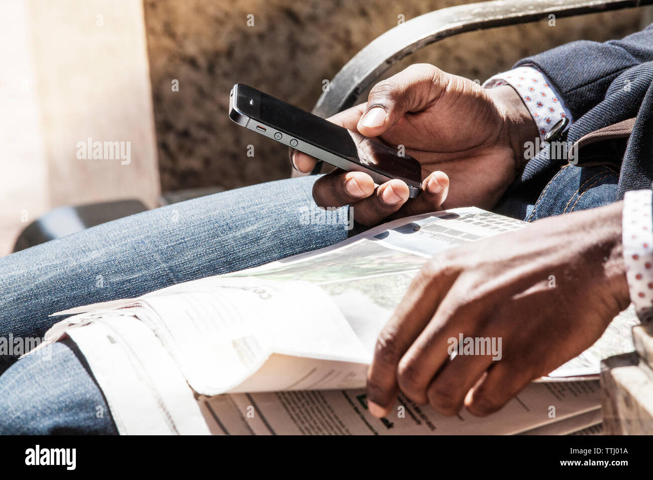 Sezione mediana di uomo con smart phone e giornale Foto Stock