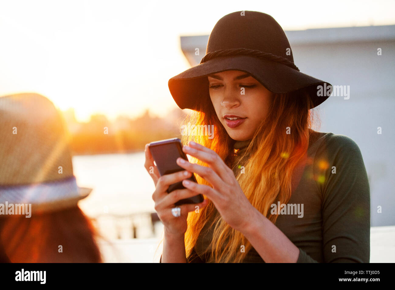 Donna che utilizza il telefono cellulare durante il tramonto Foto Stock