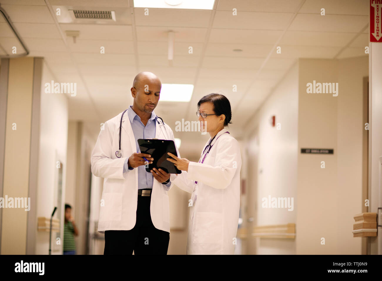 Medico donna che mostra i rapporti di sesso maschile medico permanente, mentre in ospedale Foto Stock