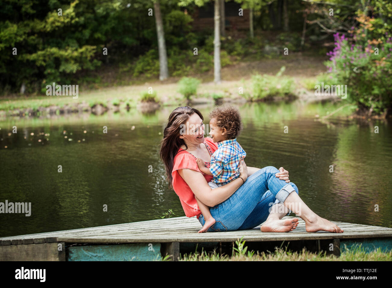 La famiglia felice seduto sul molo al lago Foto Stock