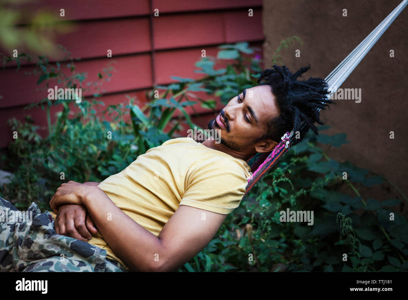 Uomo che guarda lontano mentre vi rilassate sulla amaca in Prato Foto Stock