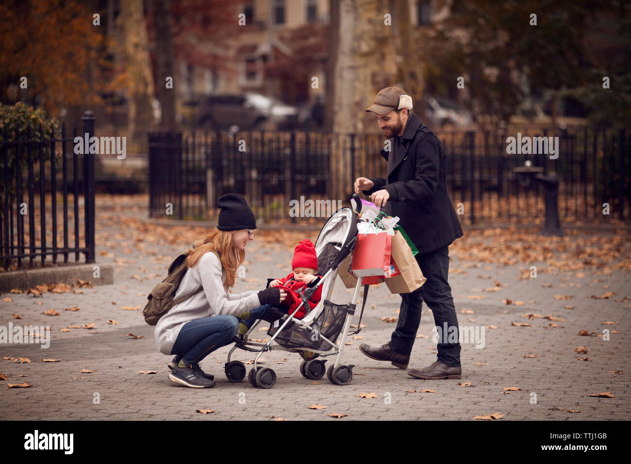 Uomo che guarda la donna mantenendo la bambina in passeggino in posizione di parcheggio Foto Stock