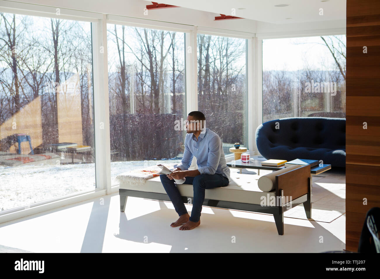 Uomo con giornale comodamente seduti sul divano di casa Foto Stock