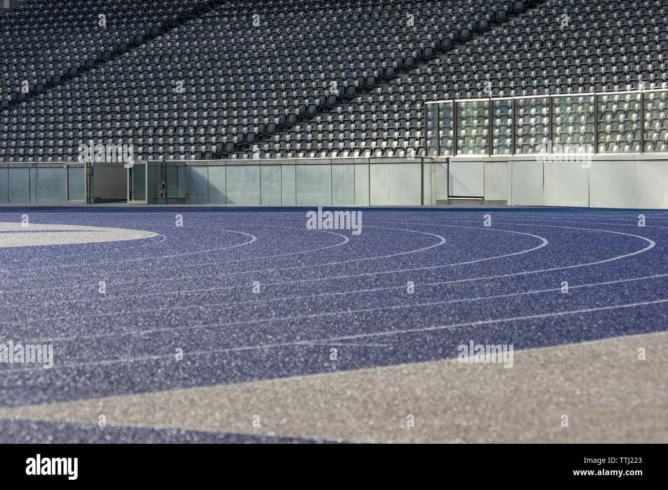 Curva con il bagnato in tartan blu acceso via in stadio olimpico di Berlino Foto Stock