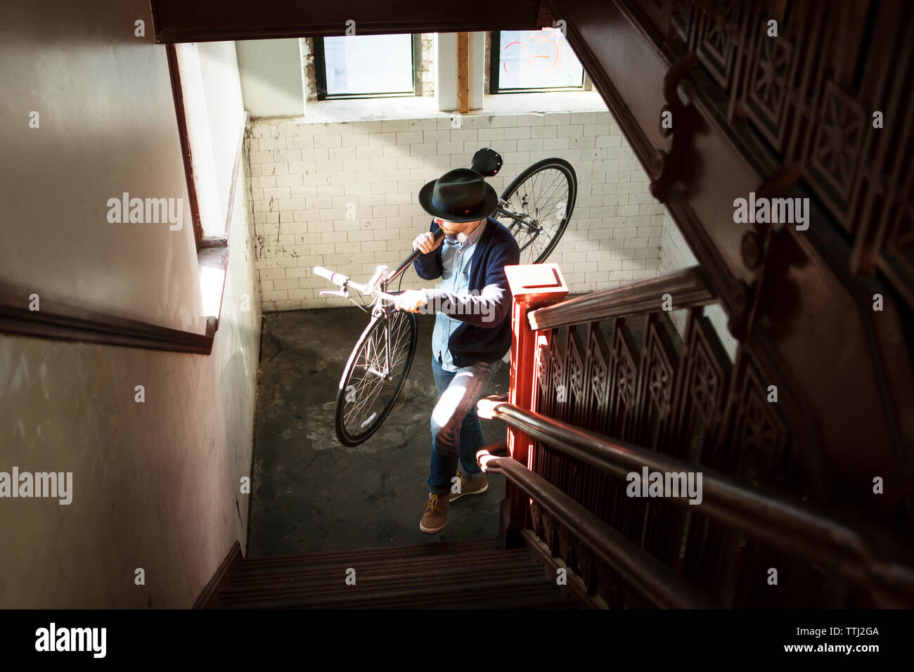 Elevato angolo di visione dell uomo che porta biciclette mentre a salire le scale di casa Foto Stock