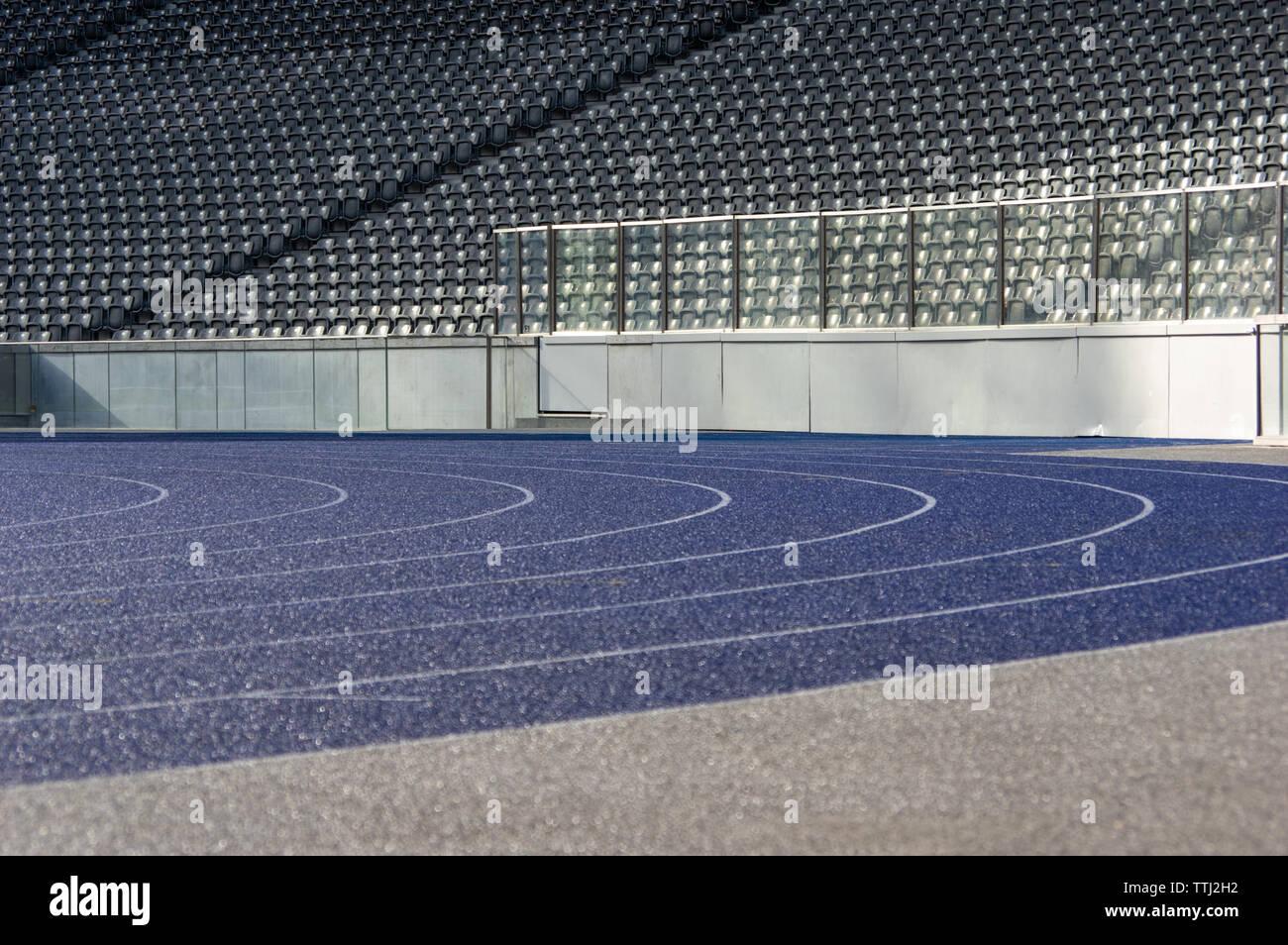 Curva con il bagnato in tartan blu acceso via in stadio olimpico di Berlino Foto Stock