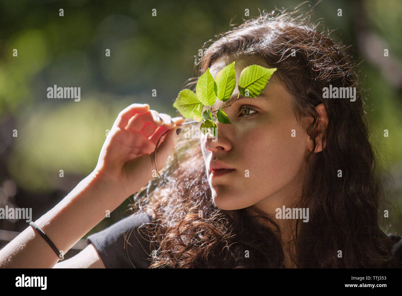 Ragazza adolescente che guarda lontano mentre si tiene lo stelo di piante Foto Stock