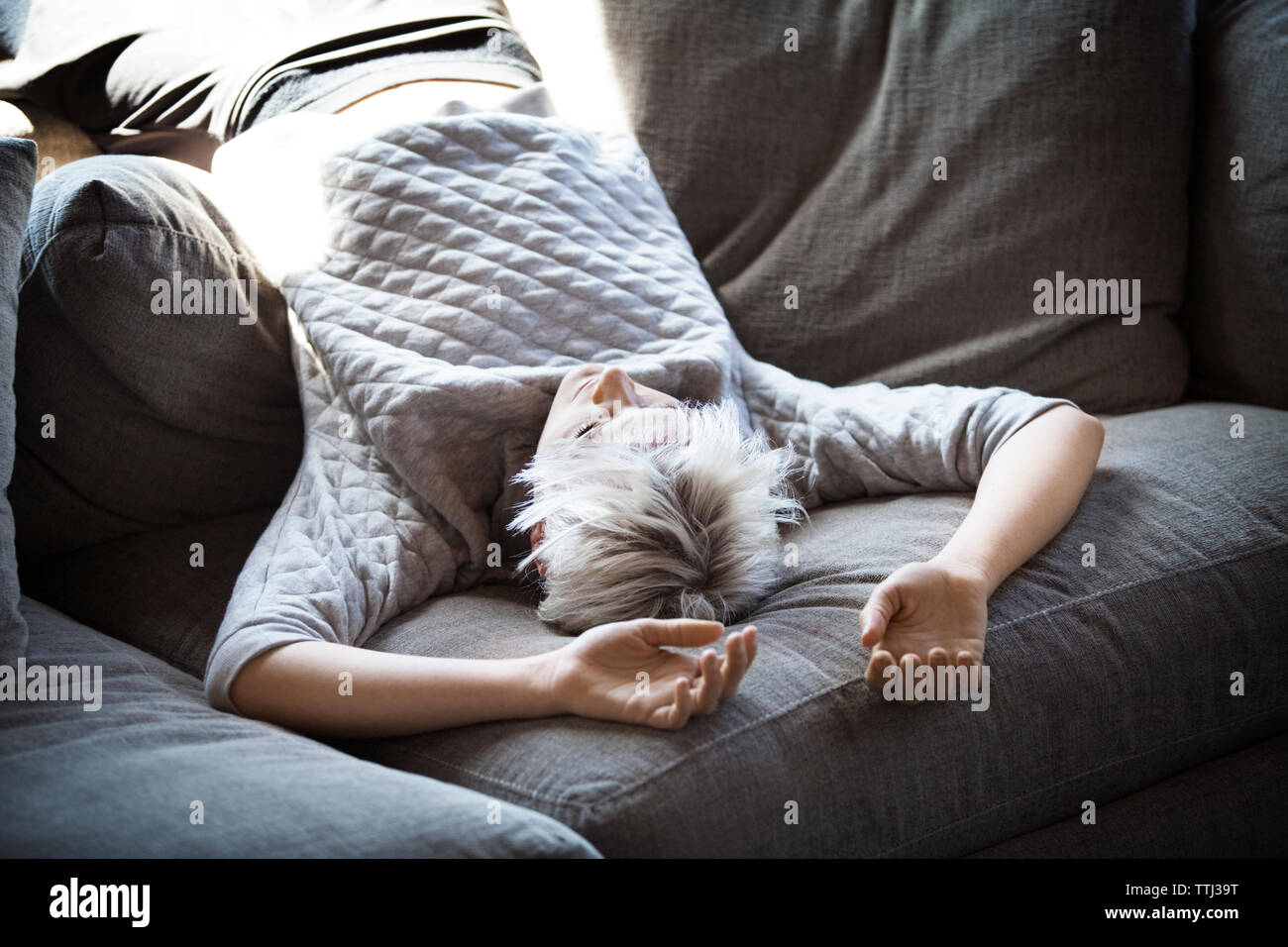 Giovane donna giaceva capovolta sul divano di casa Foto Stock