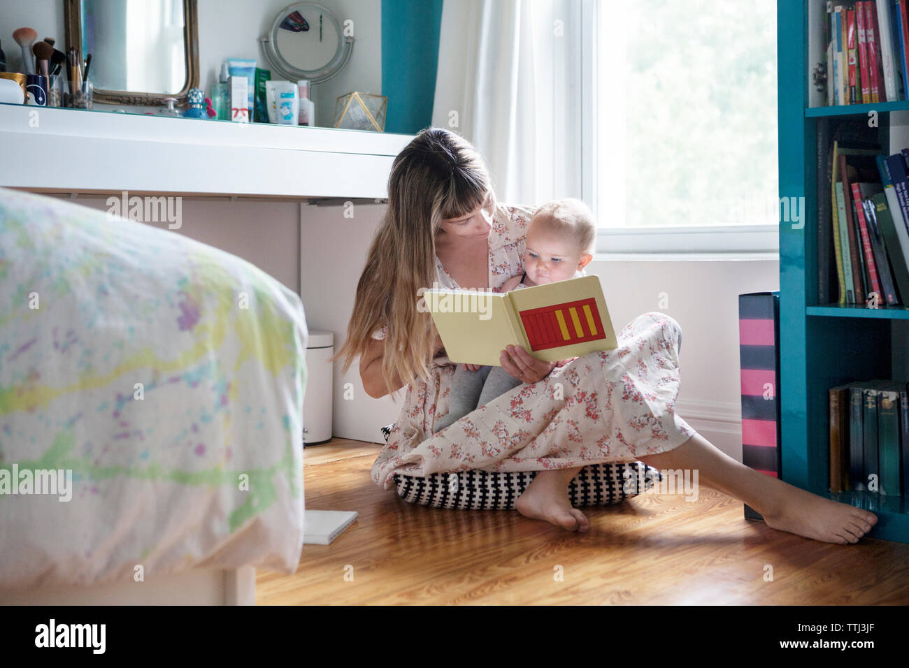 Madre libro di lettura con il bambino seduto sul pavimento a casa Foto Stock