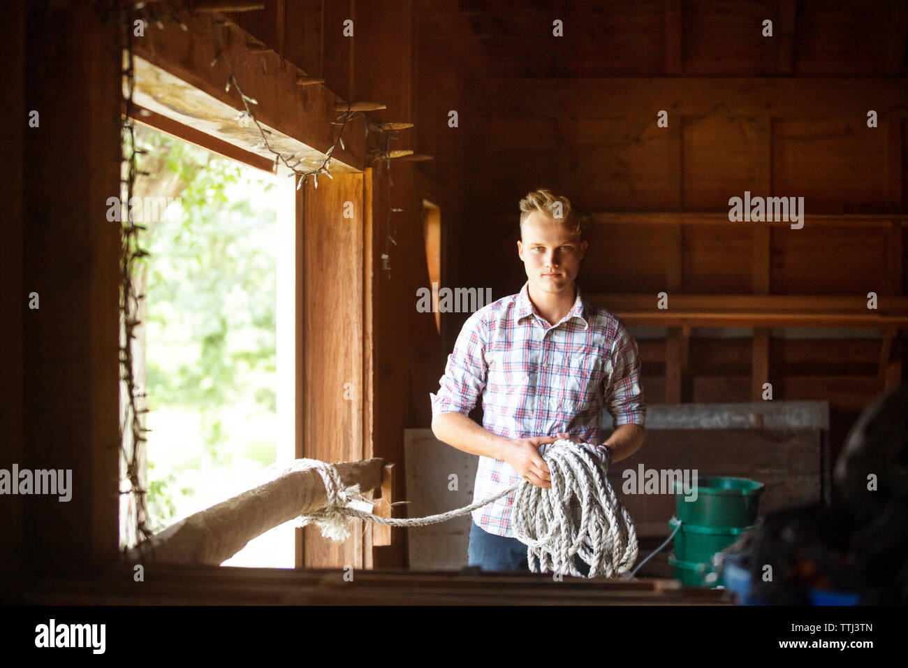 Ritratto di fiducioso rancher holding lazo nella stalla Foto Stock