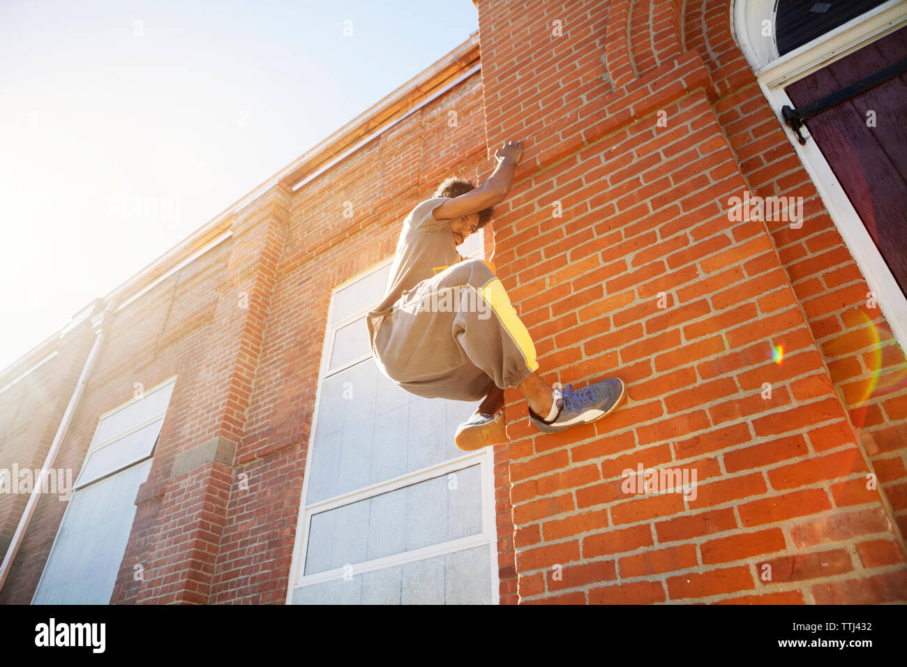Basso angolo di visione dell'uomo arrampicata parete di mattoni Foto Stock