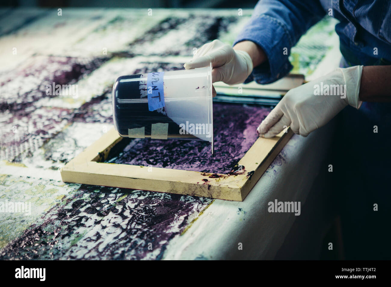 Tagliata di mano craftswoman versando il liquido su schermo di seta durante il lavoro in officina Foto Stock