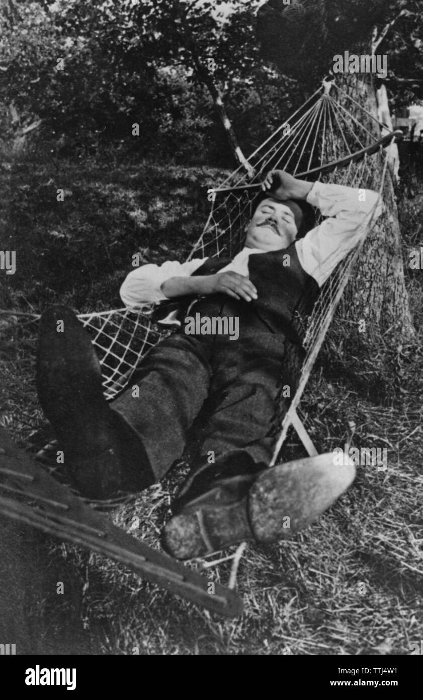 Estate nel 1940s. Un uomo è sdraiato comodo in un'amaca. Foto Stock