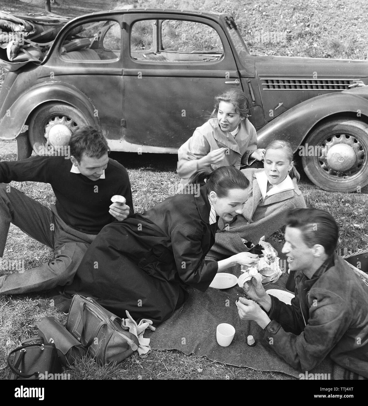 Estate con gli amici negli anni cinquanta. Un gruppo di giovani ha preso la macchina e ha un picnic sul ciglio della strada. La Svezia può 1956 Foto Stock