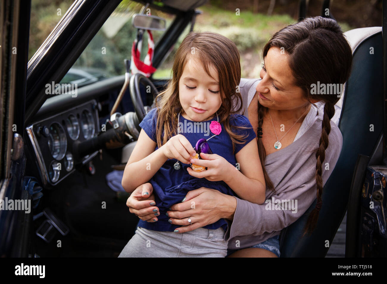 Felice madre guardando ragazza peeling arancione nel pick-up Foto Stock